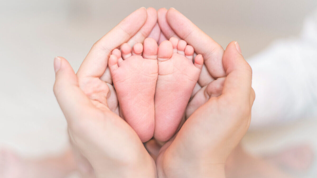 2 Hände halten Kinderfüße