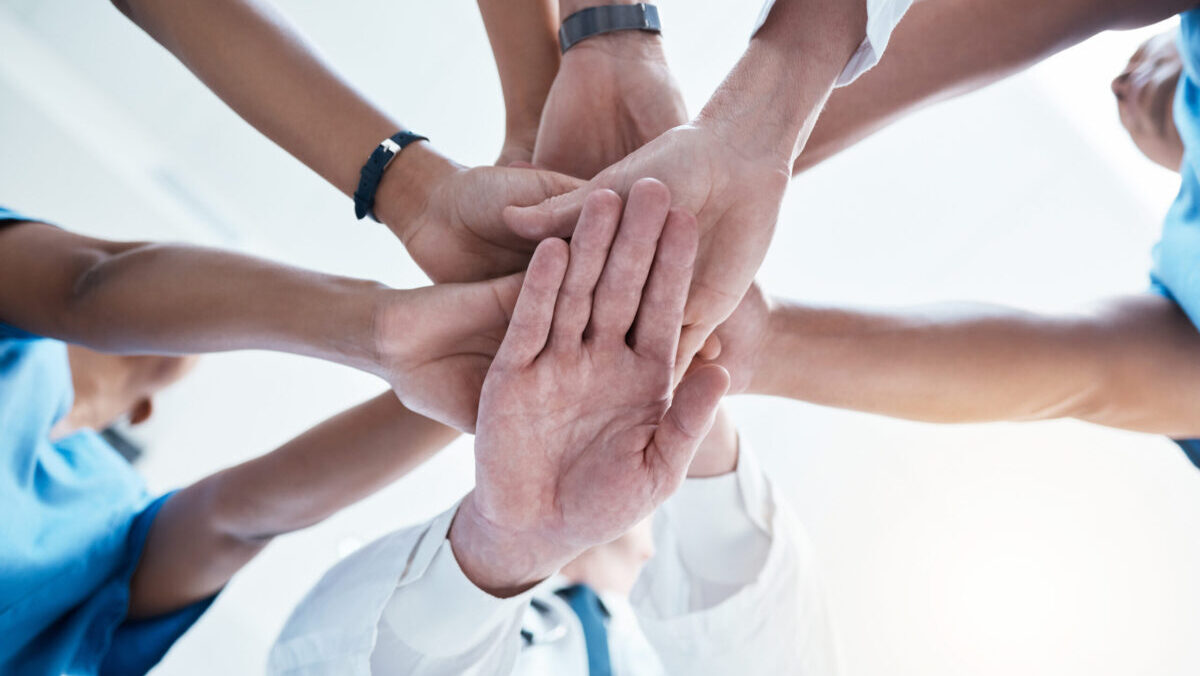 Below, group and hands stack for medical, staff and teamwork in hospital for motivation. Team, doctor and nurse with hand for collaboration, healthcare and help in community at job together in clinic.